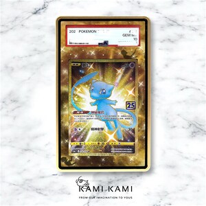 May include: A graded Pok&eacute;mon card featuring a blue Mew character with Japanese text. The card is encased in a gold-coloured frame with a GEM M 10 grade. The card has a holographic background and the text "KAMIKAMI" at the bottom.