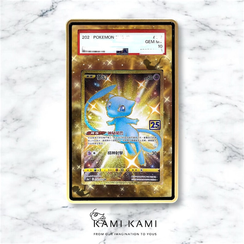 May include: A graded Pok&eacute;mon card featuring a blue Mew character with Japanese text. The card is encased in a gold-coloured frame with a GEM M 10 grade. The card has a holographic background and the text "KAMIKAMI" at the bottom.