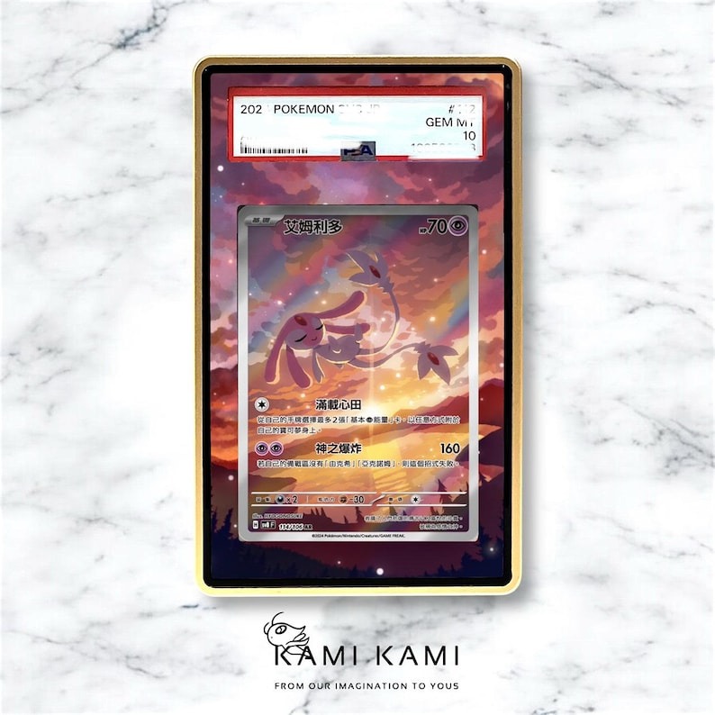 May include: A framed Pok&eacute;mon trading card featuring a pink and white creature with the text "艾姆利多". The card is encased in a gold-colored frame with a black border. The frame has a "GEM M 10" label. The background shows a sunset.