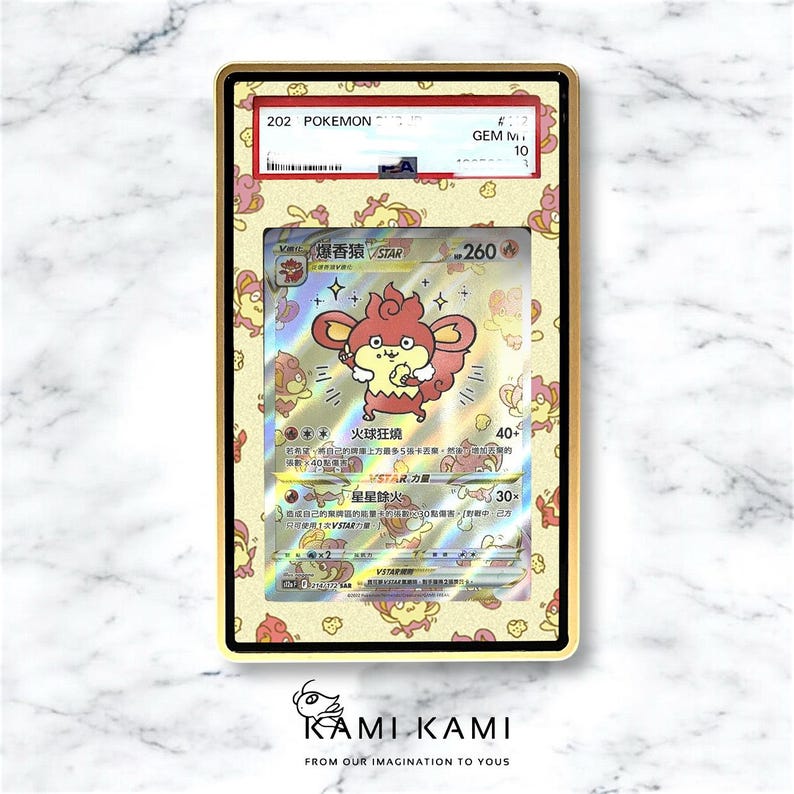 May include: A graded Pok&eacute;mon card featuring a red and yellow character with Japanese text. The card is encased in a gold-coloured holder with a decorative pattern. The text "202 Pok&eacute;mon" is visible at the top.