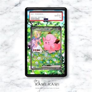 Op de afbeelding: Een Pokemon-verzamelkaart met een speciale, zeldzame kunstversie van het personage Lillie en haar Pokemon, een roze en witte Jigglypuff. De kaart is beoordeeld met GEM MT 10. De kaarttekst luidt "Lillie's Jigglypuff EX" en "Fairy Zone".