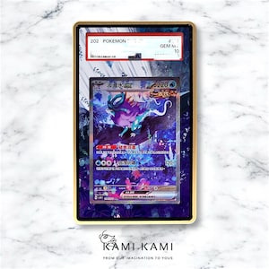 以下が含まれることがあります： 金色のフレームに収められた、Suicune EXのイラストが描かれたポケモンカード。カードには日本語のテキストとGEM MINT 10のグレードが記載されています。背景は、Kami Kamiのロゴが入った花柄のデザインです。
