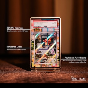 Puede incluir: Un marco de aleaci&oacute;n de aluminio dorado encierra una carta coleccionable de Pok&eacute;mon, con una ilustraci&oacute;n de Charmander. La tarjeta est&aacute; protegida por vidrio templado y es resistente al 95% de los rayos UV. El marco se muestra sobre un soporte transparente.