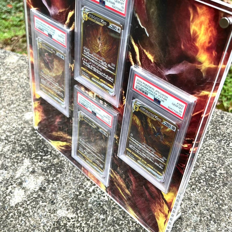 Puede incluir: Una exhibici&oacute;n con cuatro cartas coleccionables de Pok&eacute;mon clasificadas en estuches protectores. Las cartas tienen dise&ntilde;os dorados y negros, con texto en japon&eacute;s. La exhibici&oacute;n tiene un fondo abstracto y ardiente y est&aacute; montada sobre un soporte acr&iacute;lico transparente.