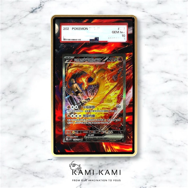 May include: A graded Pok&eacute;mon card featuring a fiery illustration of a character with the text "202 POKEMON" and "GEM MINT 10". The card is encased in a gold-colored frame, with the KAMI KAMI logo at the bottom.