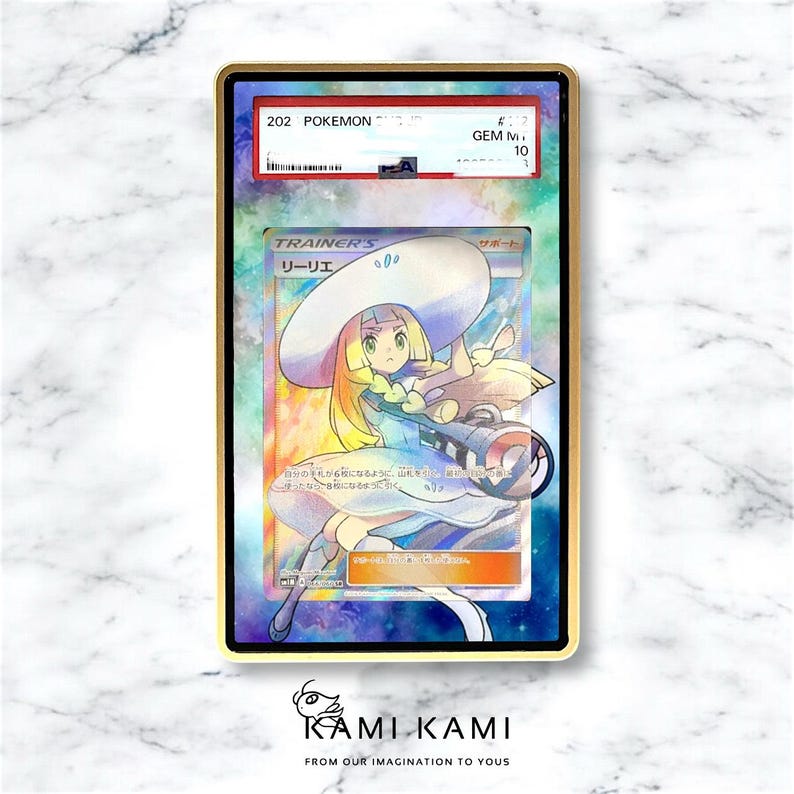 May include: A graded Pok&eacute;mon card featuring the character Lillie, with Japanese text, in a gold-coloured case. The card has a colourful background and the text "TRAINER'S" is visible. The card is graded GEM MINT 10.