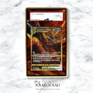 May include: A gold-framed Pokémon trading card featuring a gold and brown illustration of a creature with blue and purple accents. The card has Japanese text and a red and white label at the top. The card is graded GEM M 10.