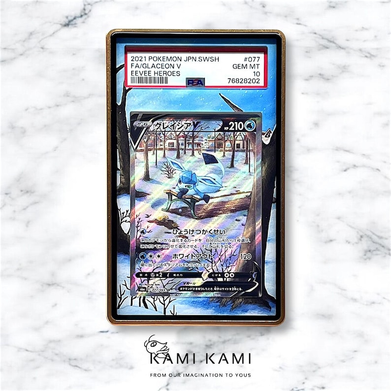 K&ouml;nnte beinhalten: Eine blaue und wei&szlig;e Pokemon-Sammelkarte mit Glaceon V aus dem Set Eeve Heroes. Die Karte ist mit GEM MT 10 von PSA bewertet und hat die Nummer 077. Die Karte zeigt Glaceon, das auf einer Bank in einem verschneiten Wald sitzt.