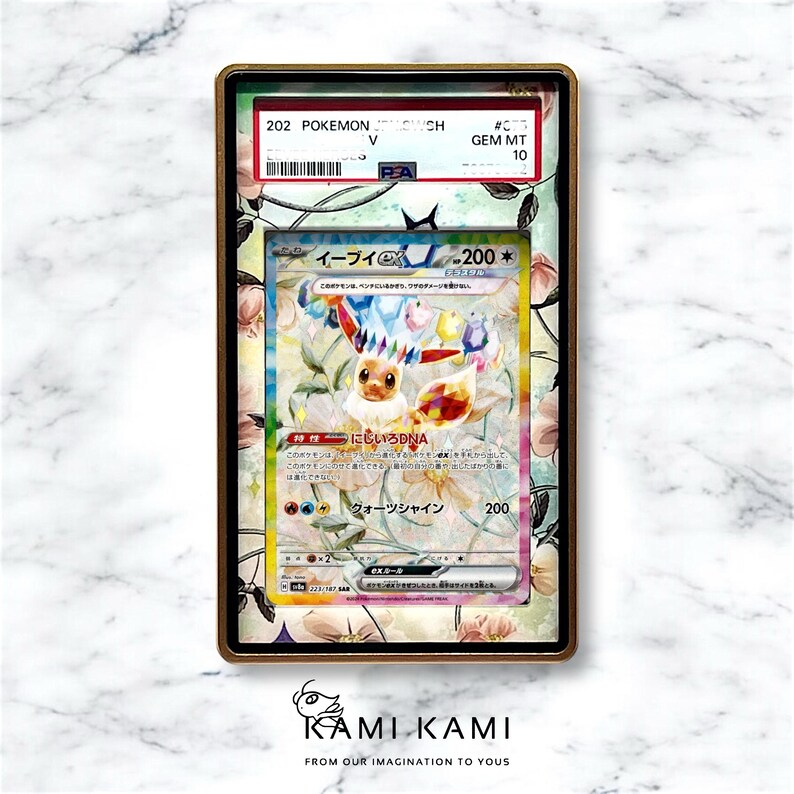 Puede incluir: Una carta de comercio de Pokemon clasificada con Eevee, un Pokemon parecido a un zorro marr&oacute;n claro con una melena y una cola arco&iacute;ris. La carta est&aacute; en una caja protectora con una calificaci&oacute;n Gem Mint 10. El texto de la carta dice "Eevee EX 200*" y "ADN arco&iacute;ris".