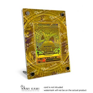 Könnte beinhalten: Ein goldfarbener Display-Rahmen mit einer Sammelkarte. Die Karte zeigt ein holografisches Design mit japanischem Text und einer Charakterillustration. Der Rahmen hat einen Ständer und ist mit vier schwarzen Schrauben befestigt. Der Text "KAMI KAMI" steht unten.