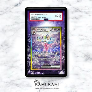 May include: A Pokemon trading card in a black display case. The card has a vibrant illustration of a creature with Japanese text. The top of the case reads "SPECIAL ART RARE" and "GEM MT 10". The bottom of the case has the text "KAMI KAMI".