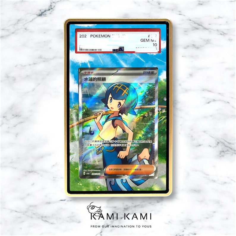 May include: A graded Pok&eacute;mon trading card featuring a character illustration with blue and white tones, holding a wooden staff. The card is encased in a gold-colored frame with a black backing. The card is labeled "202 POKEMON" and "GEM MINT 10".