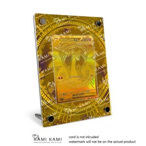 May include: A gold-colored display case with a trading card inside. The case has a decorative border and is supported by a silver stand. The card features a golden dragon illustration and Japanese text. The text "KAMI KAMI" is visible.