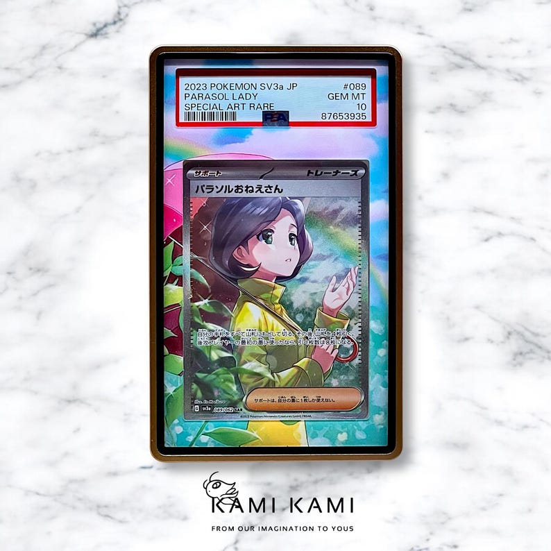 May include: A graded Pok&eacute;mon card featuring "Parasol Lady" artwork. The card is encased in a protective holder with text indicating it's a Special Art Rare from 2023. The card's artwork depicts a woman under a rainbow-colored umbrella.