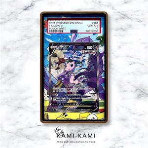 K&ouml;nnte beinhalten: Gerahmte Pok&eacute;mon-Sammelkarte mit Mew V aus dem Fusion Arts Set. Die Karte zeigt eine rosa und lila Mew-Illustration mit japanischem Text. Der Rahmen enth&auml;lt ein Etikett mit Set-Details und der Bewertung GEM MT 10.