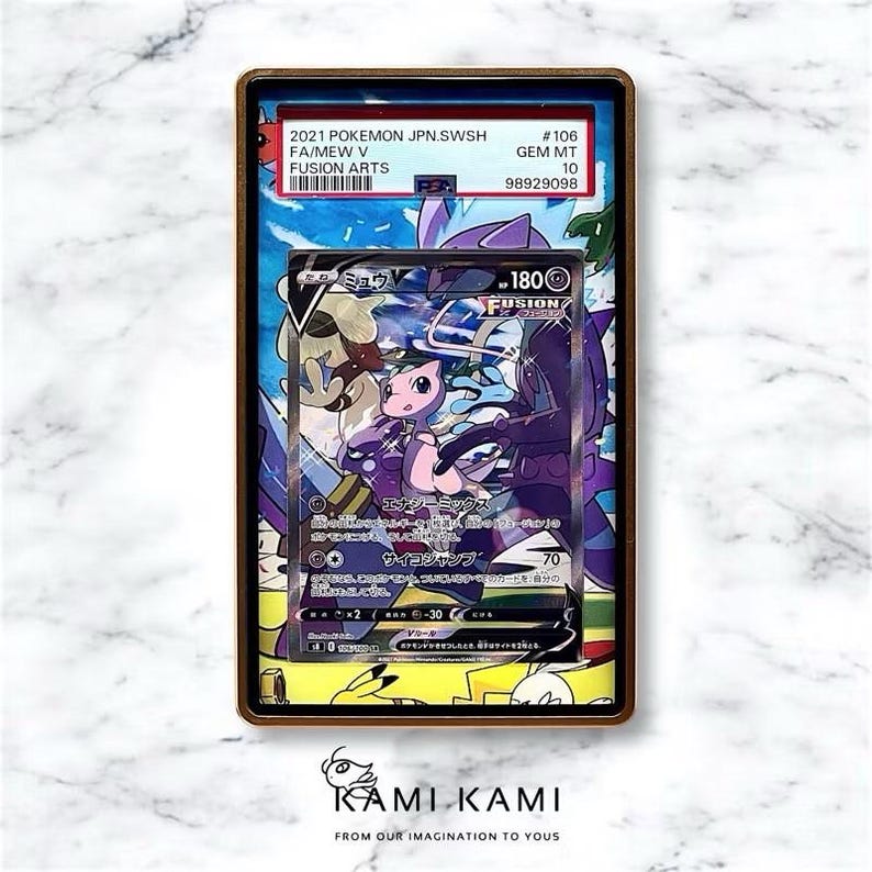 K&ouml;nnte beinhalten: Gerahmte Pok&eacute;mon-Sammelkarte mit Mew V aus dem Fusion Arts Set. Die Karte zeigt eine rosa und lila Mew-Illustration mit japanischem Text. Der Rahmen enth&auml;lt ein Etikett mit Set-Details und der Bewertung GEM MT 10.