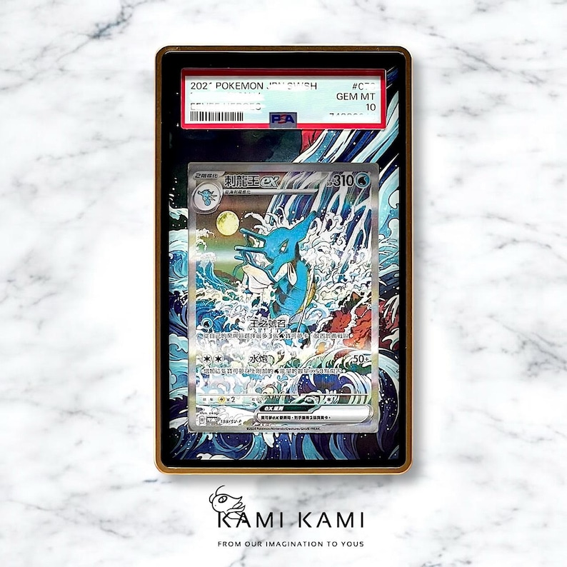 May include: A framed Pok&eacute;mon trading card featuring a blue and white aquatic creature illustration. The card is encased in a gold-colored frame with text that includes "202 Pok&eacute;mon" and "GEM MT 10". The card has Japanese text.