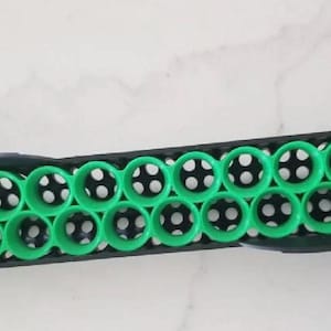 Könnte beinhalten: Ein schwarzer und grüner Kunststoff-Aufbewahrungsbehälter mit 24 runden Fächern. Der Behälter ist für die Aufbewahrung von kleinen Gegenständen wie Perlen, Knöpfen oder anderen Bastelartikeln konzipiert.