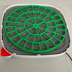 Könnte beinhalten: Ein weißer Lebensmitteldehydrator mit einem grünen Netztablett. Das Tablett ist zum Trocknen von Lebensmitteln konzipiert.
