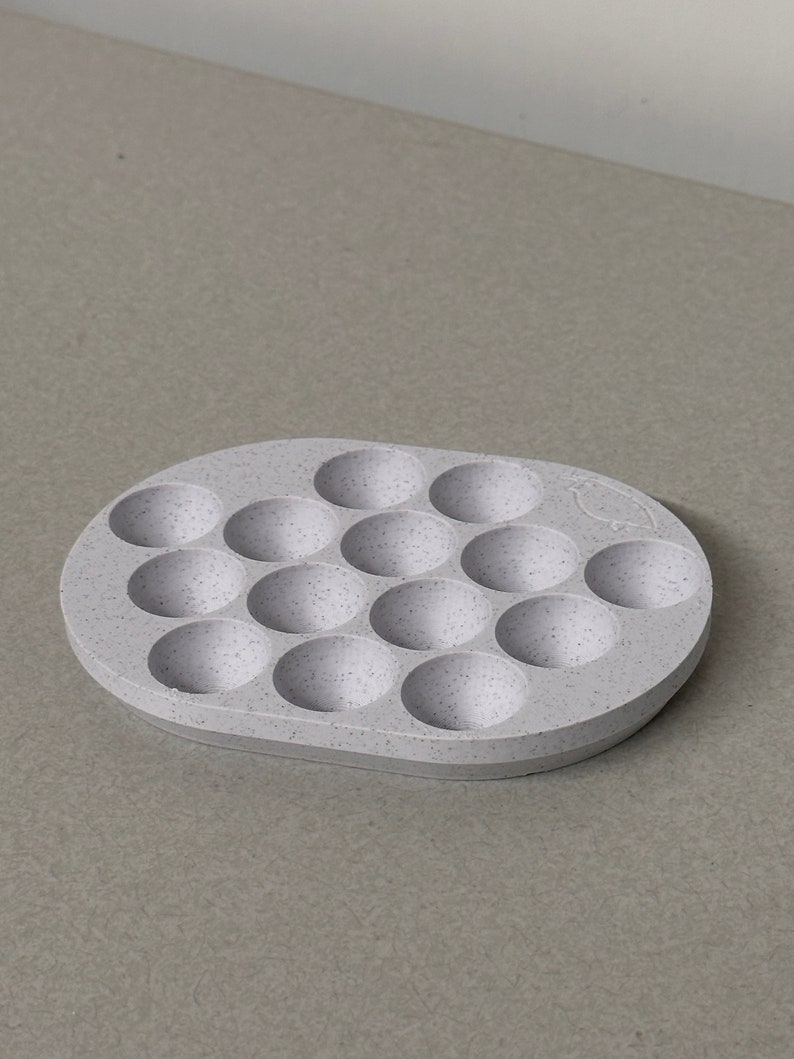May include: A light gray silicone tray with 16 round indentations. The tray is speckled with white flecks.