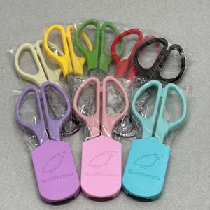 May include: A set of ten colorful small scissors with a quail logo on the handle. The scissors are packaged in clear plastic bags.