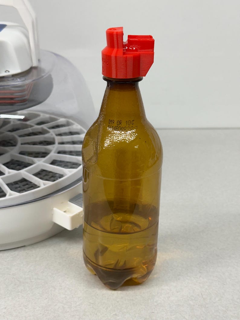 May include: A clear, brown plastic bottle with a red cap. The bottle contains a clear liquid. The cap is a bright red color. The bottle has a label with the text "019 OR 10C".