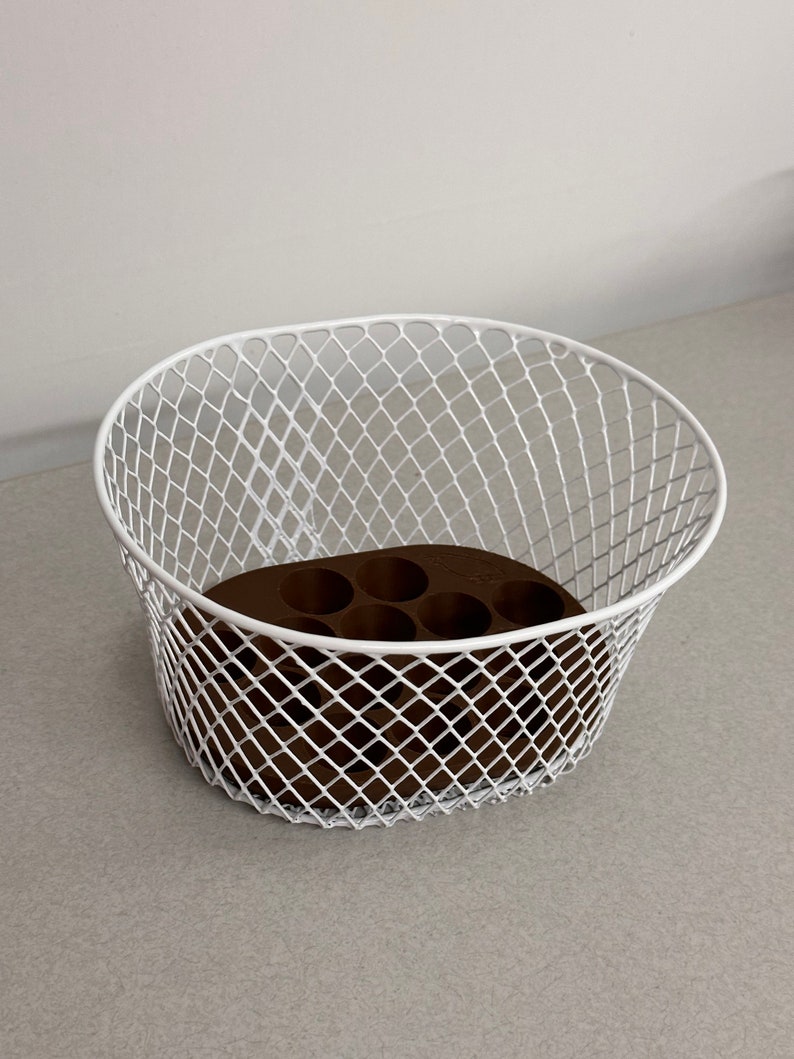 May include: White metal wire basket with a brown plastic insert with six round holes. The basket is oval shaped and has a diamond pattern.