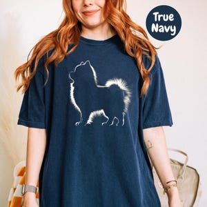 a woman wearing a blue t - shirt with a white dog on it