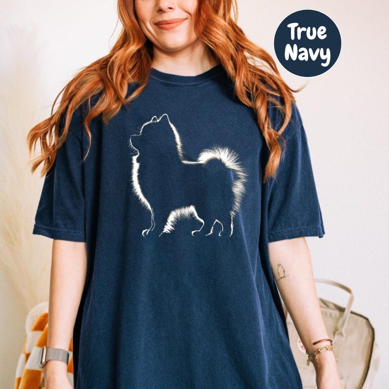 a woman wearing a blue t - shirt with a white dog on it