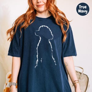A woman with long red hair wearing a navy blue t-shirt with a white silhouette of a dog.