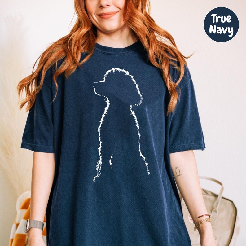 A woman with long red hair wearing a navy blue t-shirt with a white silhouette of a dog.