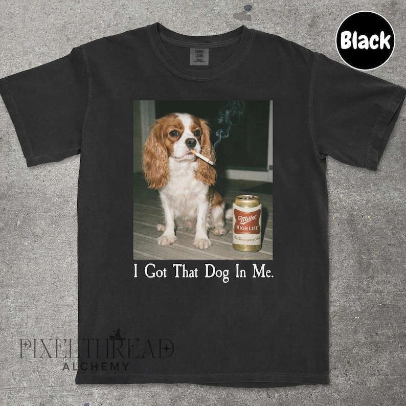 A black t-shirt with a printed image of a dog smoking a cigarette next to a can of Miller High Life beer.