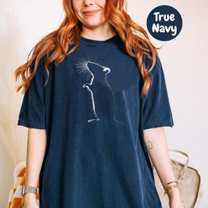 a woman wearing a blue t - shirt with a picture of a cat on it