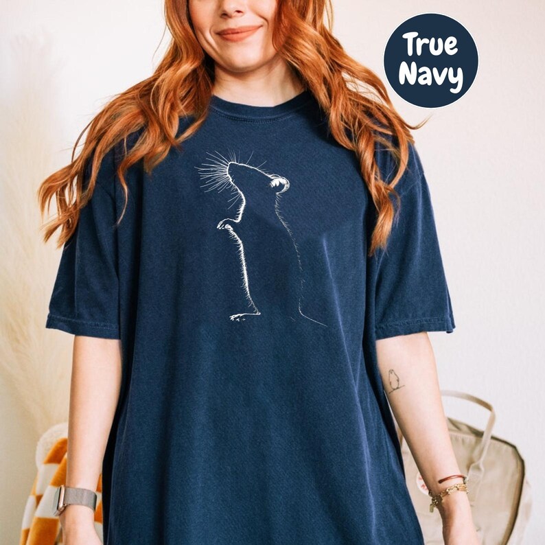 a woman wearing a blue t - shirt with a picture of a cat on it