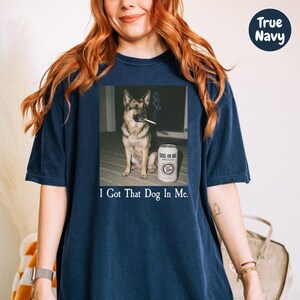A woman wearing a navy blue t-shirt with a graphic of a dog smoking a cigarette and the text "I Got That Dog In Me" printed on it.