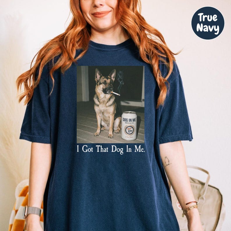 A woman wearing a navy blue t-shirt with a graphic of a dog smoking a cigarette and the text "I Got That Dog In Me" printed on it.