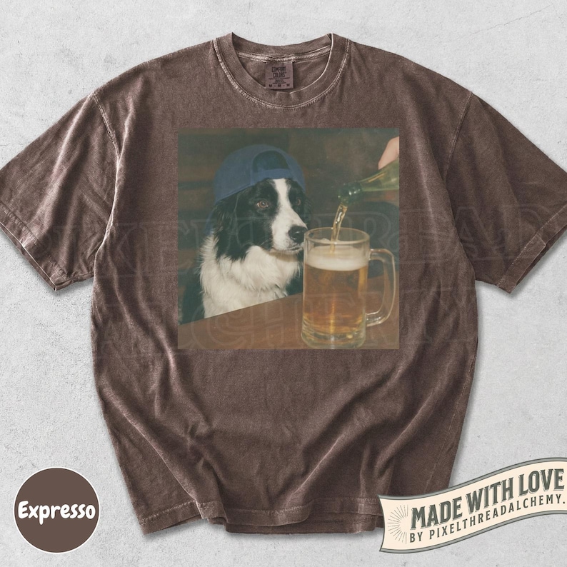 May include: Brown t-shirt featuring a graphic of a Border Collie wearing a blue cap, watching beer being poured into a pint glass. The shirt has a vintage look, with the word "Expresso" on the bottom left.