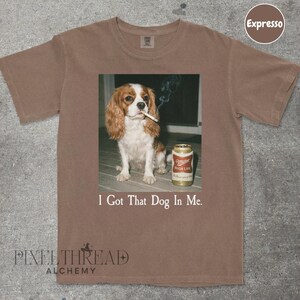 A brown t-shirt with a printed image of a dog holding a can of Miller High Life beer.