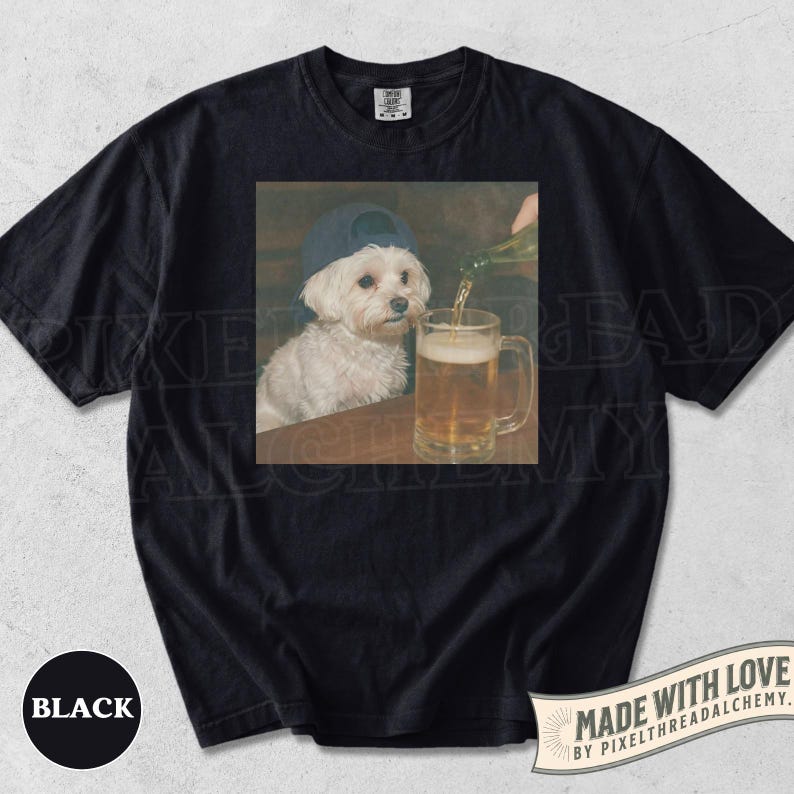 May include: Black t-shirt featuring a square image of a white dog wearing a blue baseball cap, sitting at a table while beer is poured into a mug. The shirt has the word "BLACK" printed on the bottom left.