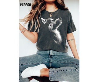May include: A woman wearing a dark gray t-shirt with a white silhouette of a husky dog's head. She is wearing blue jeans and white sneakers.