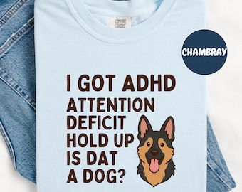 May include: Light blue t-shirt with the text "I GOT ADHD ATTENTION DEFICIT HOLD UP IS DAT A DOG?" and a cartoon dog graphic. The shirt has a crew neck and the brand name "COMFORT COLORS" is visible.
