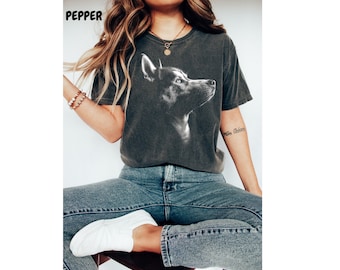 May include: A dark gray t-shirt with a black and white image of a husky dog's head looking to the right. The dog's eyes are blue.