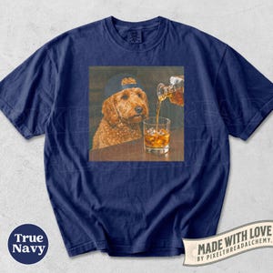 K&ouml;nnte beinhalten: Marineblaues T-Shirt mit einem quadratischen Aufdruck eines Hundes mit Kappe, der beobachtet, wie Whisky in ein Glas mit Eis gegossen wird. Das Shirt tr&auml;gt die Aufschrift "True Navy" und "Made with Love".