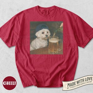 May include: Red t-shirt featuring a graphic of a white dog wearing a blue cap, sitting at a table while beer is poured into a mug. The shirt has the word "CHILL" printed on the bottom left.