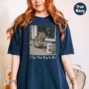 A woman wearing a navy blue t-shirt with a graphic of a rat smoking a cigarette and the text "I Got That Dog In Me" printed on it.