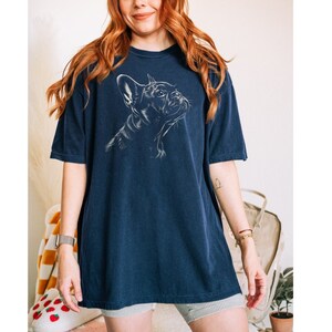 a woman with red hair wearing a blue t - shirt