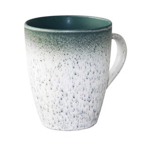 May include: A white and green ceramic mug with a speckled glaze. The mug has a rounded shape and a handle.