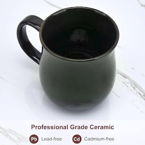 May include: A dark green ceramic mug with a glossy finish and a curved handle. The text below the mug reads: Professional Grade Ceramic, Pb Lead-free, and Cd Cadmium-free. The mug has a rounded body and a smooth, reflective surface texture.