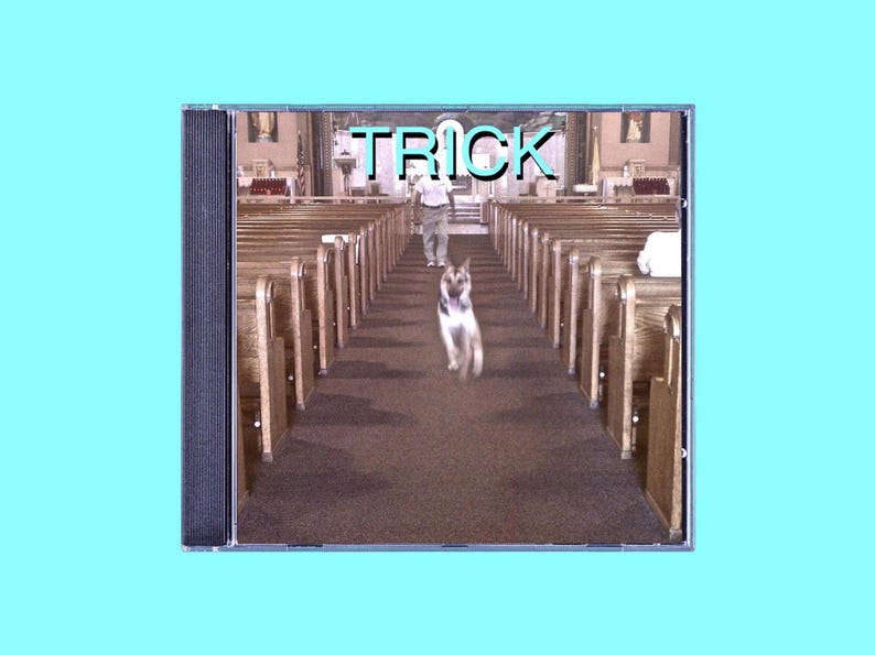 K&ouml;nnte beinhalten: Ein CD-Geh&auml;use mit einem Foto eines Hundes, der einen Kirchenweg entlangl&auml;uft. Der Text "TRICK" ist in Blau auf dem Geh&auml;use aufgedruckt.