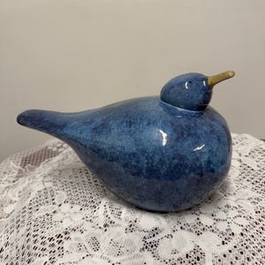 May include: A ceramic bird figurine in shades of blue with a glossy finish. The bird has a rounded body, a small head, and a pointed beak. The figurine is a decorative item.